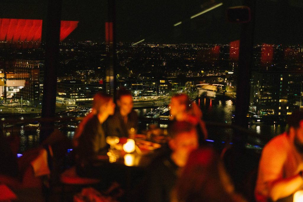 Bij het nieuwe menu van Madam Skybar & Restaurant wordt óók je smaakervaring naar een hoger niveau getild Wie nog niet bekend was met de hoogste rooftopbar van Amsterdam, moet niet alleen langs gaan voor het prachtige uitzicht. Vanaf 20 april serveren ze bij Madam Skybar & Restaurant namelijk allerlei nieuwe smaken, en die bevallen goed. Het is niet niets, zo op de 20ste verdieping van de A’DAM toren met uitzicht over het water en de skyline van de hoofdstad. Omdat de ruimte aan alle kanten met ramen omgeven is, kijk je je ogen uit waar je ook zit. Maar ook binnen ziet Madam Skybar & Restaurant er prachtig uit, waar een mix aan Aziatische prints, rode lichten en donkere kleuren de mood bepalen. Dat brengt ons ook direct naar het nieuwe menu van Madam, waar Asian-fused shared dining de focus is. Vaak krijg je bij gerechten om te delen héle kleine porties, maar dat is hier gelukkig niet het geval. Ook staan er verrassende gerechten op het menu met brede invloeden. Denk aan bijvoorbeeld smaken uit Korea (garnalentoast met gochujang), India (frisse Pani Puri met komkommer, avocado en een beetje pit) en Japan (met een scala aan mochi ijs). Ze zijn niet bang om te experimenteren, zowel de opmaak van de borden als de smakencombinaties maken dat duidelijk. Bij veel gerechten krijg je een rookmachine meegeserveerd – wat nogmaals benadrukt dat je tussen de wolken zit. Heel bijzonder is ook de silken tofu crème brûlée met kokos, dadel en sinaasappel, die wegsmelt op je tong. Toch fijn dat ze ondanks de afwisseling aan smaken en keukens de kwaliteit behouden. En niet onbelangrijk: ook voor de vegetariër zijn er genoeg opties. Voor het échte toetje sla je het luxe cocktailmenu open, waar ook weer de verschillende Aziatische invloeden terugkomen. De cocktails worden met veel aandacht voor detail gecreëerd. De ‘Blooming love’ ziet eruit zoals het klinkt, gedecoreerd met bloemetjes en smaken van kersenbloesem, rozen en hibiscus. En bij de old fashioned met een Aziatische twist word je glas gerookt waar je bij staat. Kortom, tijdens een avond bij Madam geniet je niet alleen van een toplocatie, maar krijg je er een hele ervaring bij, waar verfijning centraal staat.